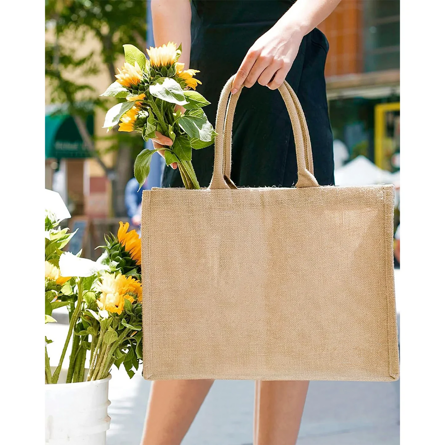 Person holding a beige jute bag with sunflowers outdoors